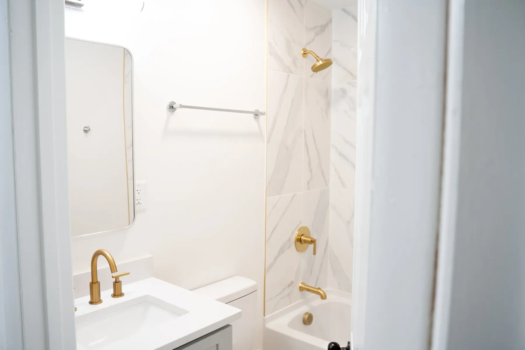 Bath with marble-look tile and brass fixtures