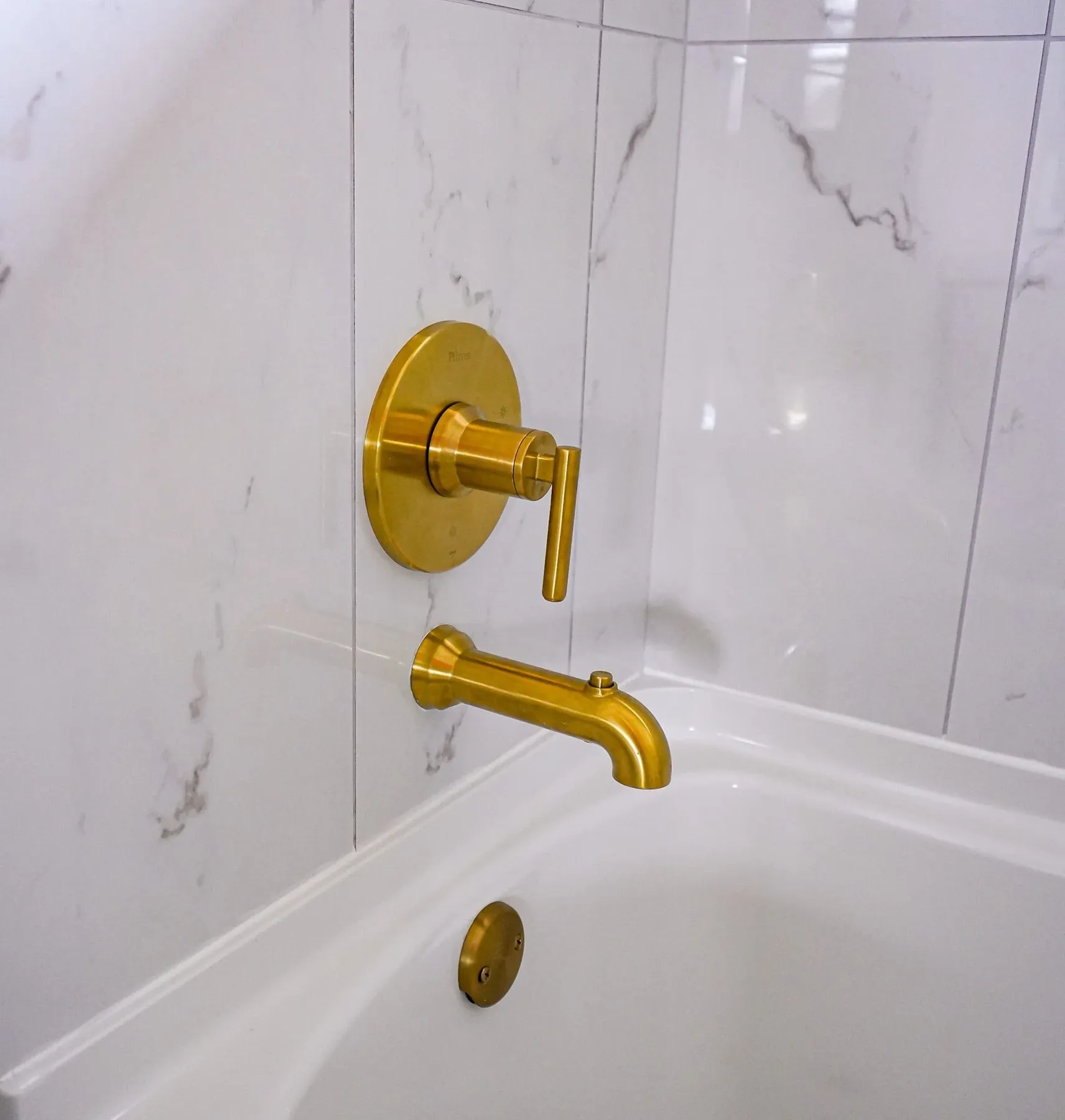 Brass tub fixtures on marble-look tile