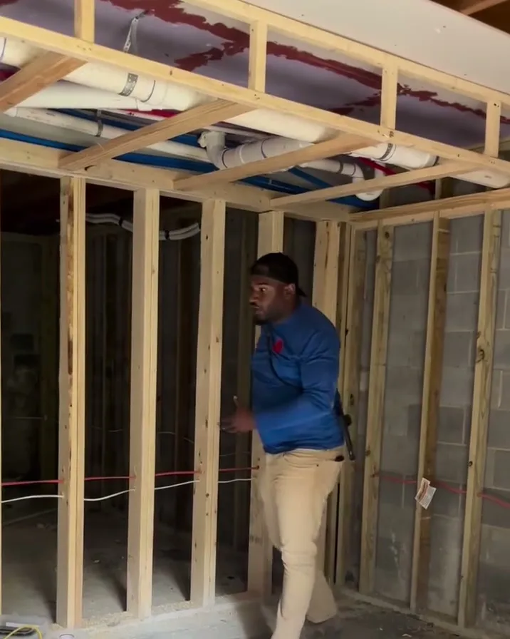 Kirk walking a framed interior with open stud walls
